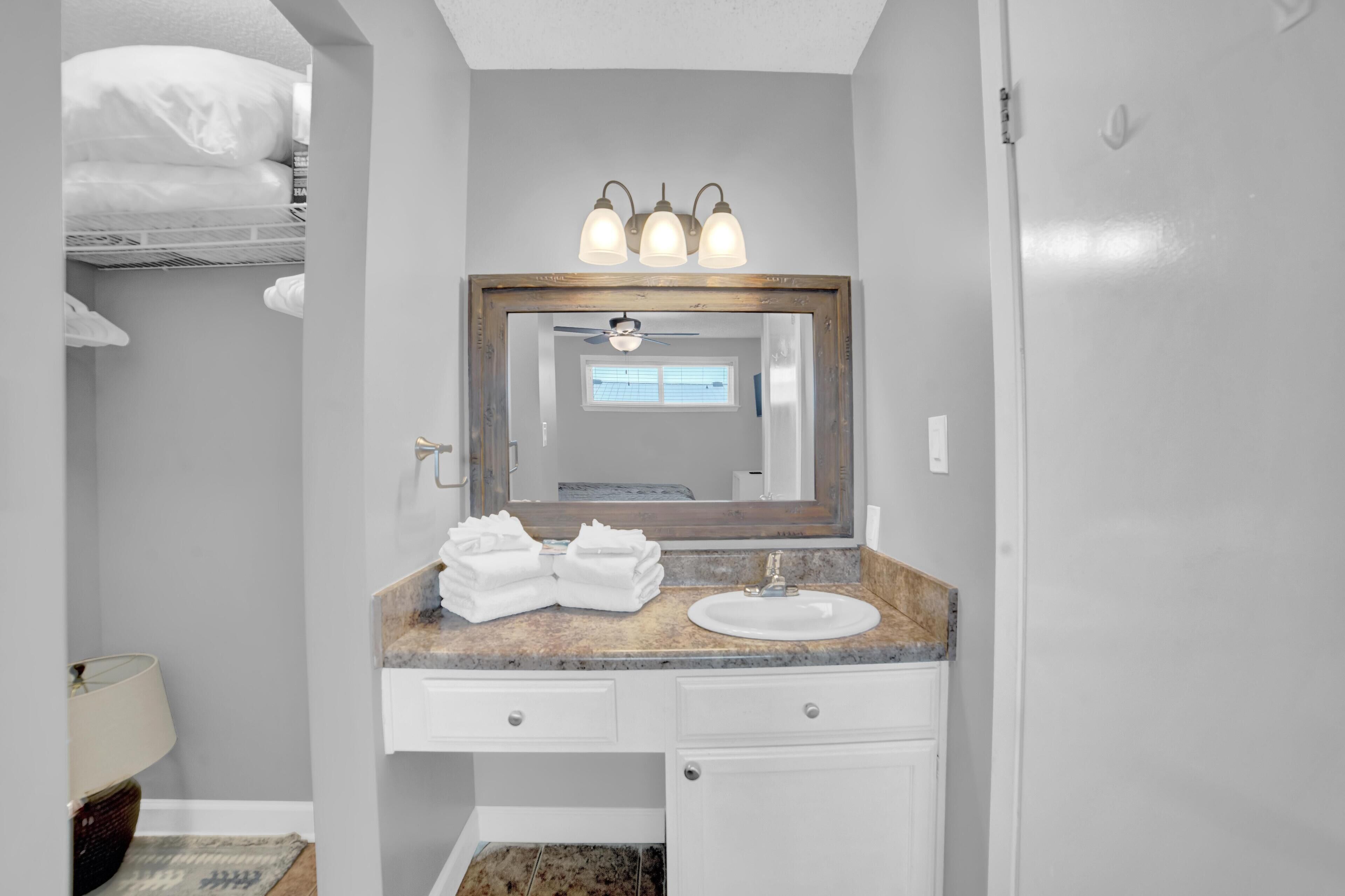 A bathroom with a vanity, a mirror, a ceiling fan, and a window.