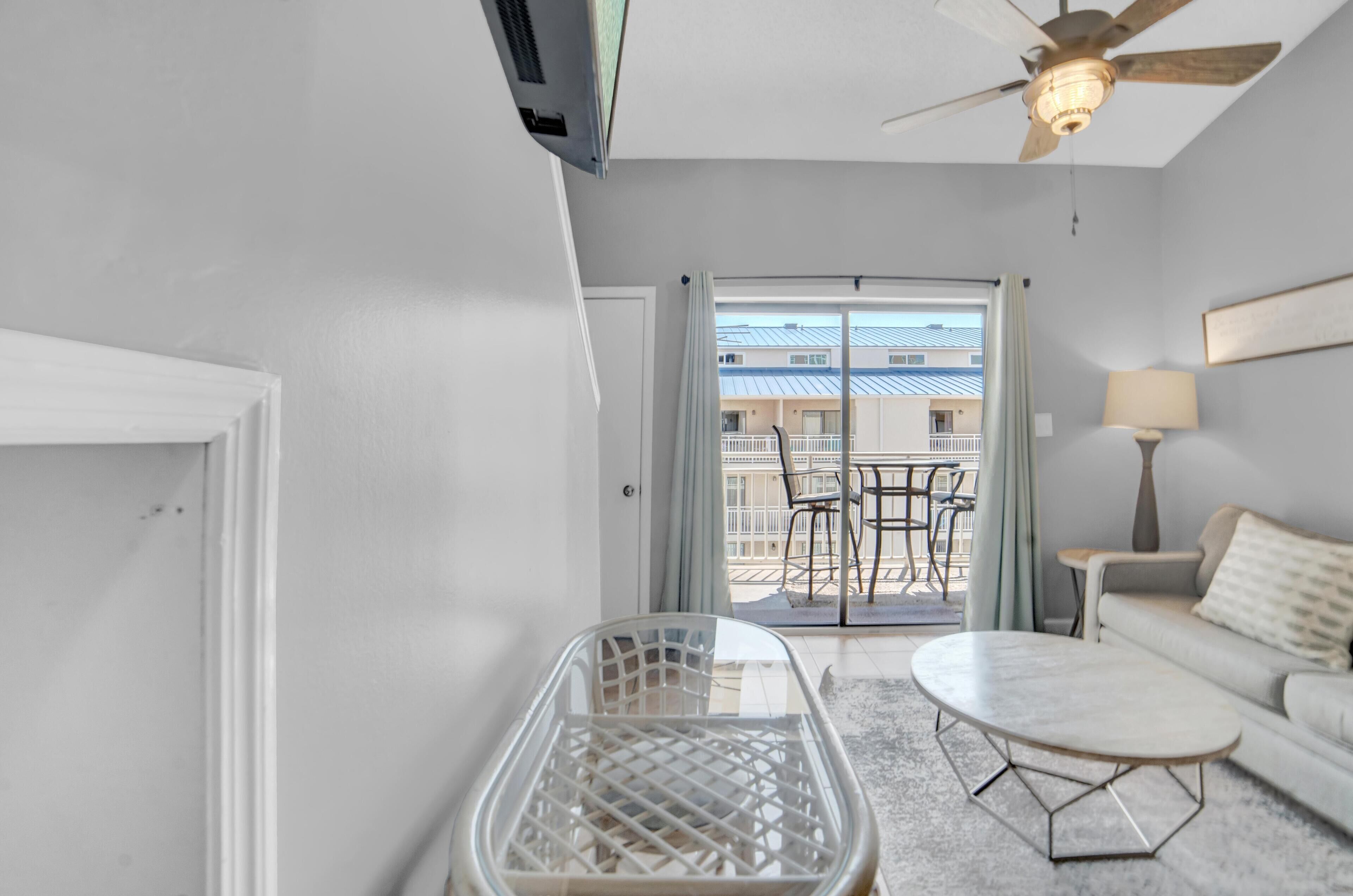 A modern hotel room with a balcony, a sofa, a coffee table, and a chair.