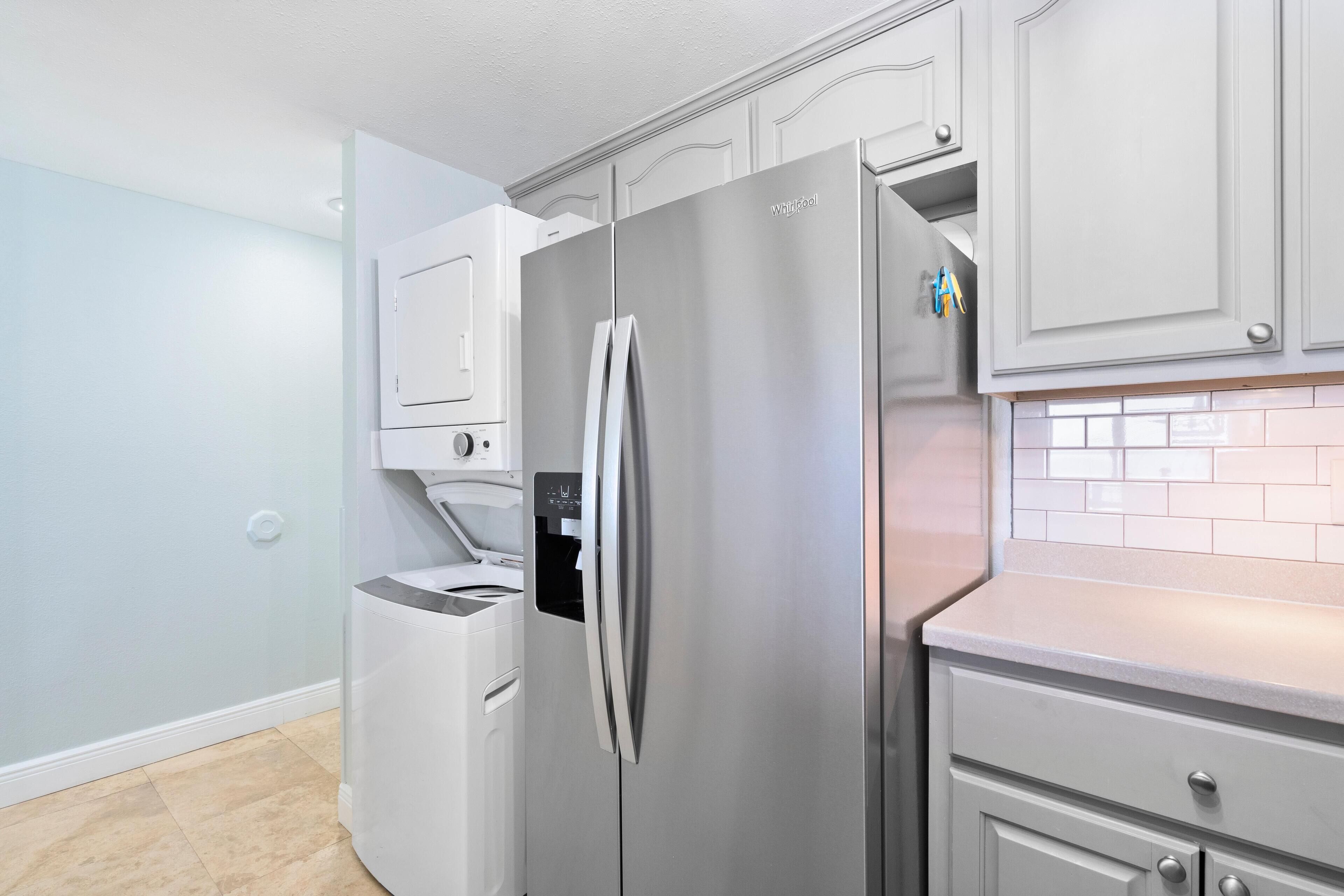A modern kitchen with a stainless steel refrigerator, a built-in dishwasher, and light blue walls.