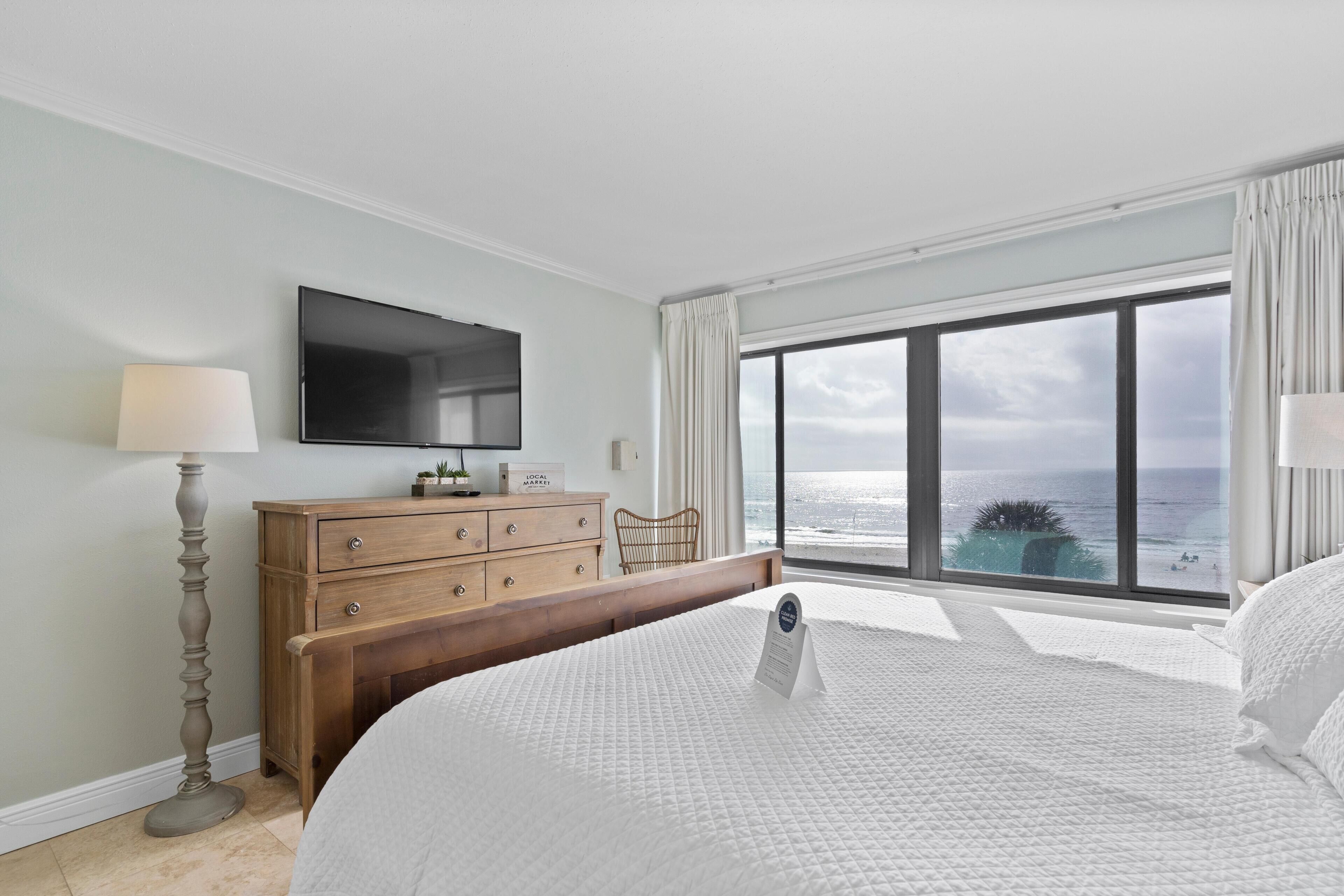 Une chambre dotée d’un grand lit, d’une commode, d’un téléviseur à écran plat et offrant une vue sur l’océan.