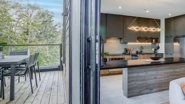 A modern kitchen with a large island, dark cabinetry, and a pendant light.