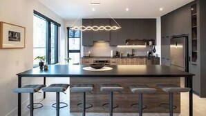 A modern kitchen with a central island, bar stools, and a pendant light.