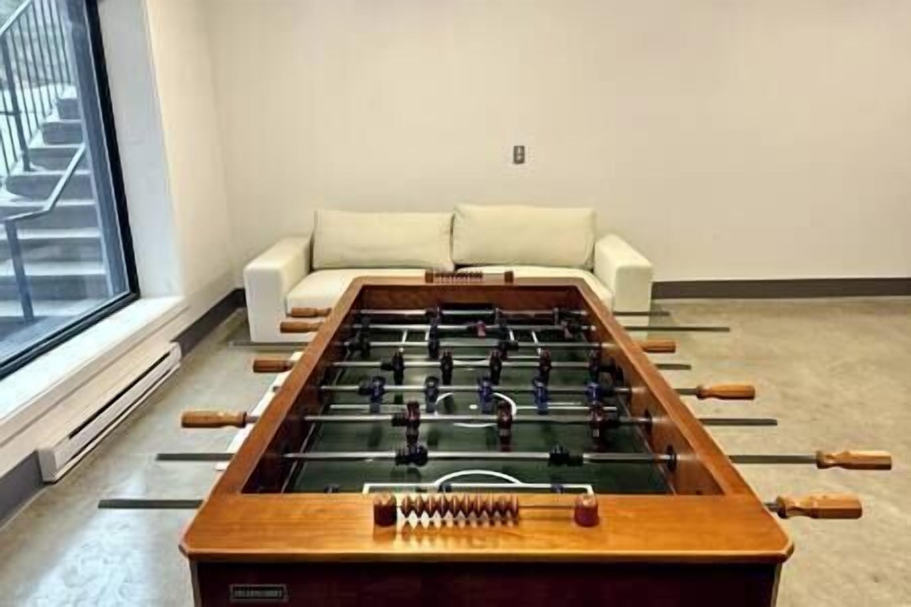 Ein Fußballtisch in einem Raum mit einem weißen Sofa und einem Fenster.