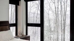 A bedroom with a large window, a bed, and a nightstand.