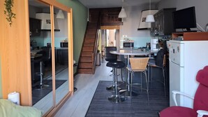 Uma cozinha moderna com área de refeições, escada e sala de estar com sofá e televisão.