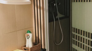 Casa de banho com chuveiro, um porta-toalhas e um dispensador de sabonete na parede.