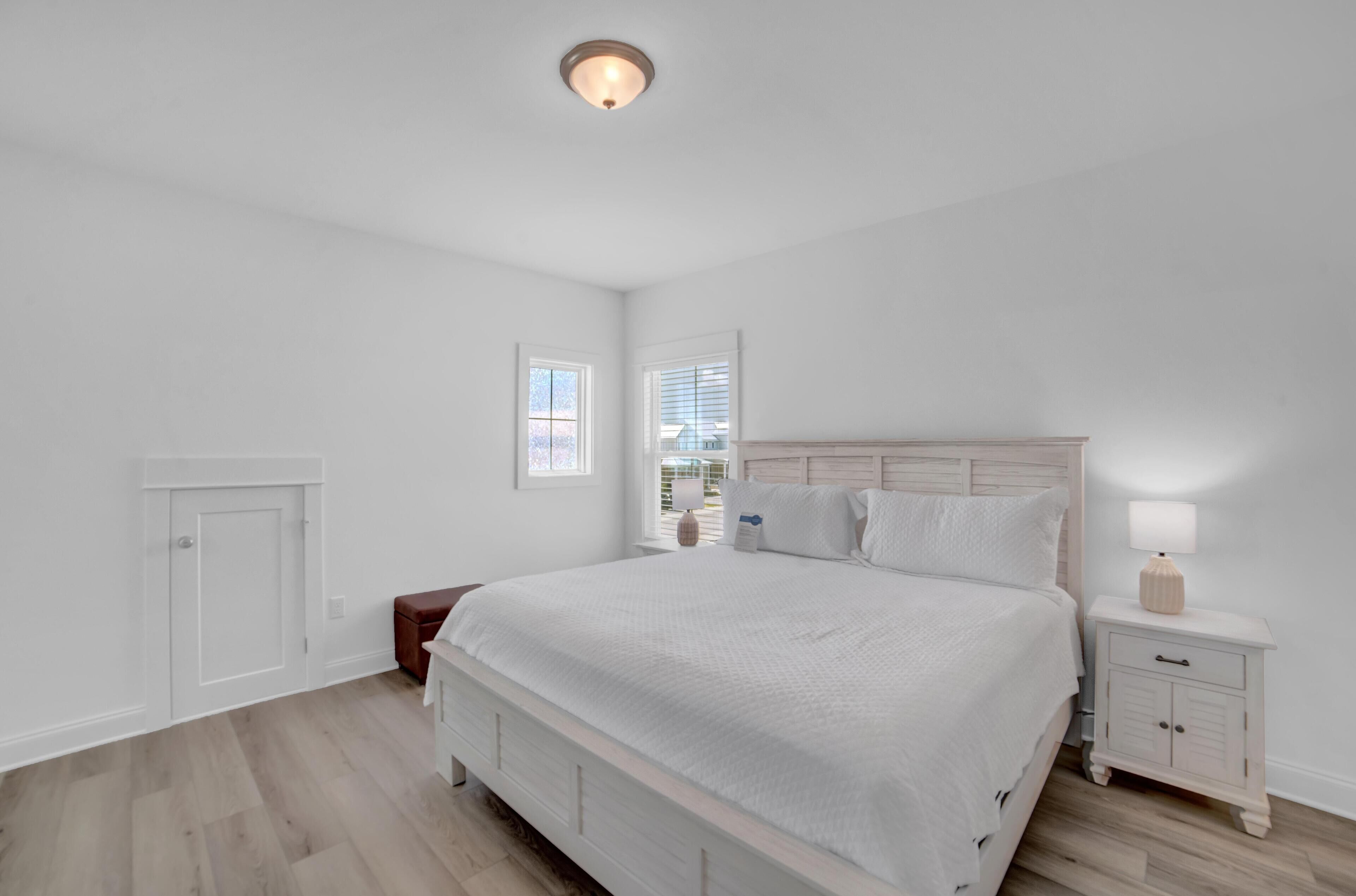 A bedroom with a large bed, a nightstand, a dresser, and a window.