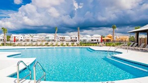 En pool med solstolar och utsikt över hotellkomplexets byggnader.