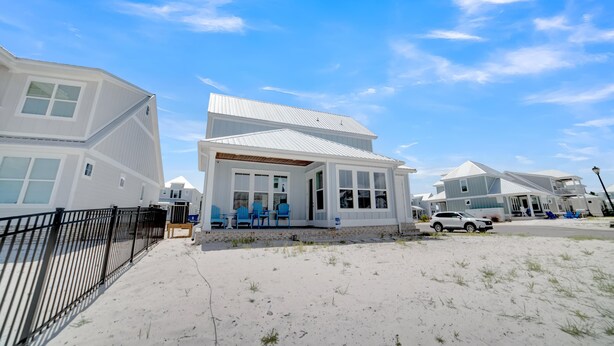 En fastighet vid stranden med ett vitt hus, en inglasad veranda och en sandstrand.