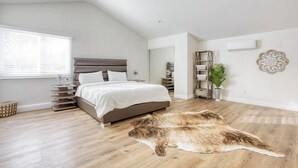 Ein Schlafzimmer mit einem Bett, Holzboden, Deckenventilator, einem Fenster mit Jalousien und einem dekorativen Teppich.