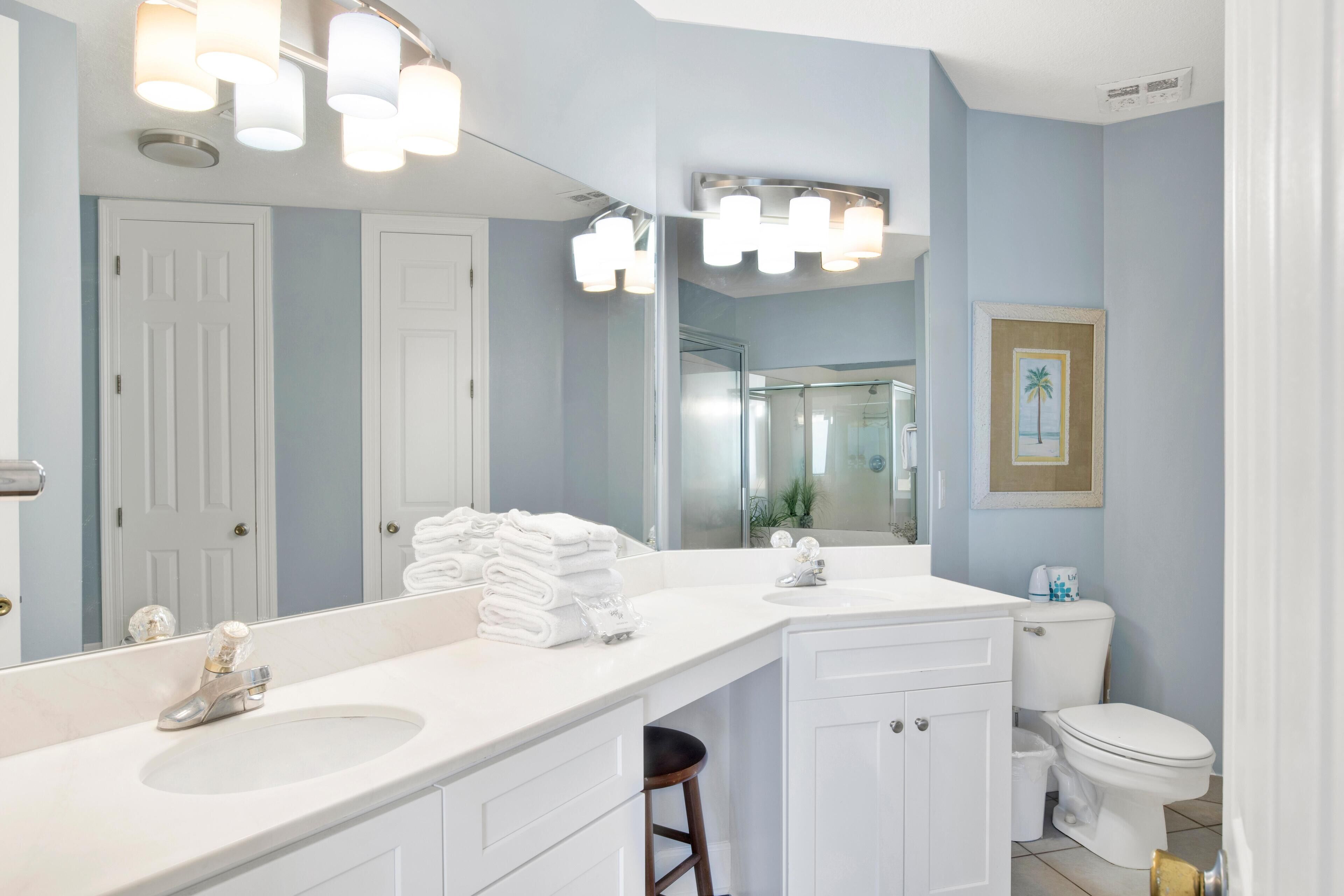 A bathroom with a white vanity, a large mirror, and a toilet.