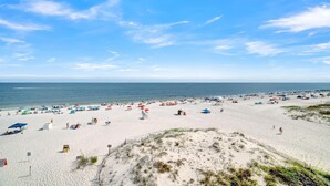 A wide beach with numerous umbrellas and beach chairs, a sandy shoreline, and a clear blue sky. - Gulf House 401 (Gulf Shores)