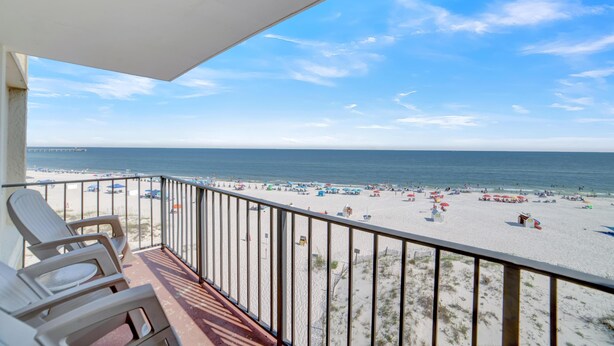 A balcony with a view of a beach, featuring beach chairs and umbrellas. - Gulf House 401 (Gulf Shores)