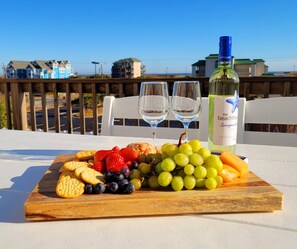 A table with a fruit platter, two wine glasses, and a bottle of wine.