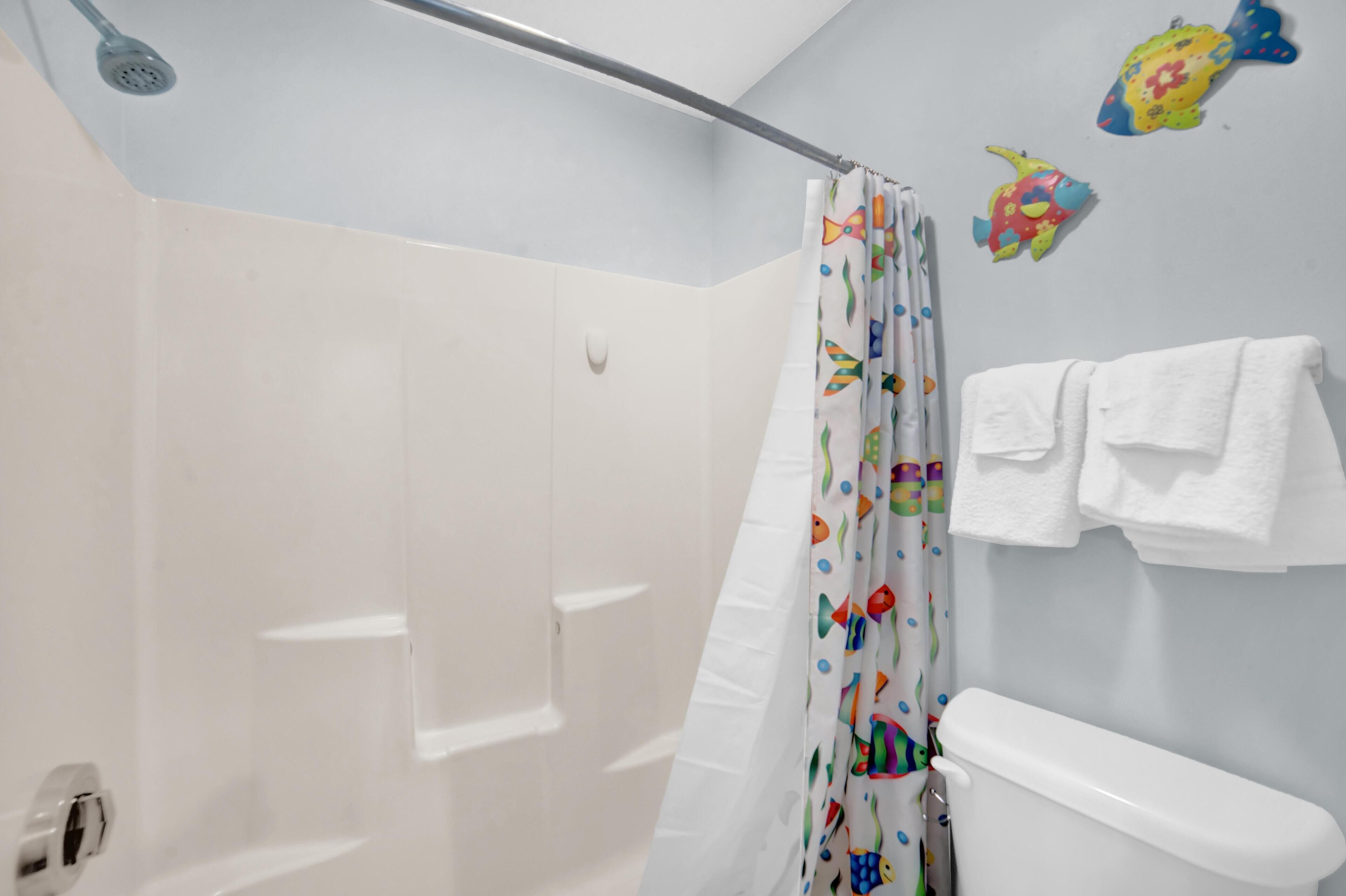 A bathroom with a shower, a toilet, and a towel rack with towels.