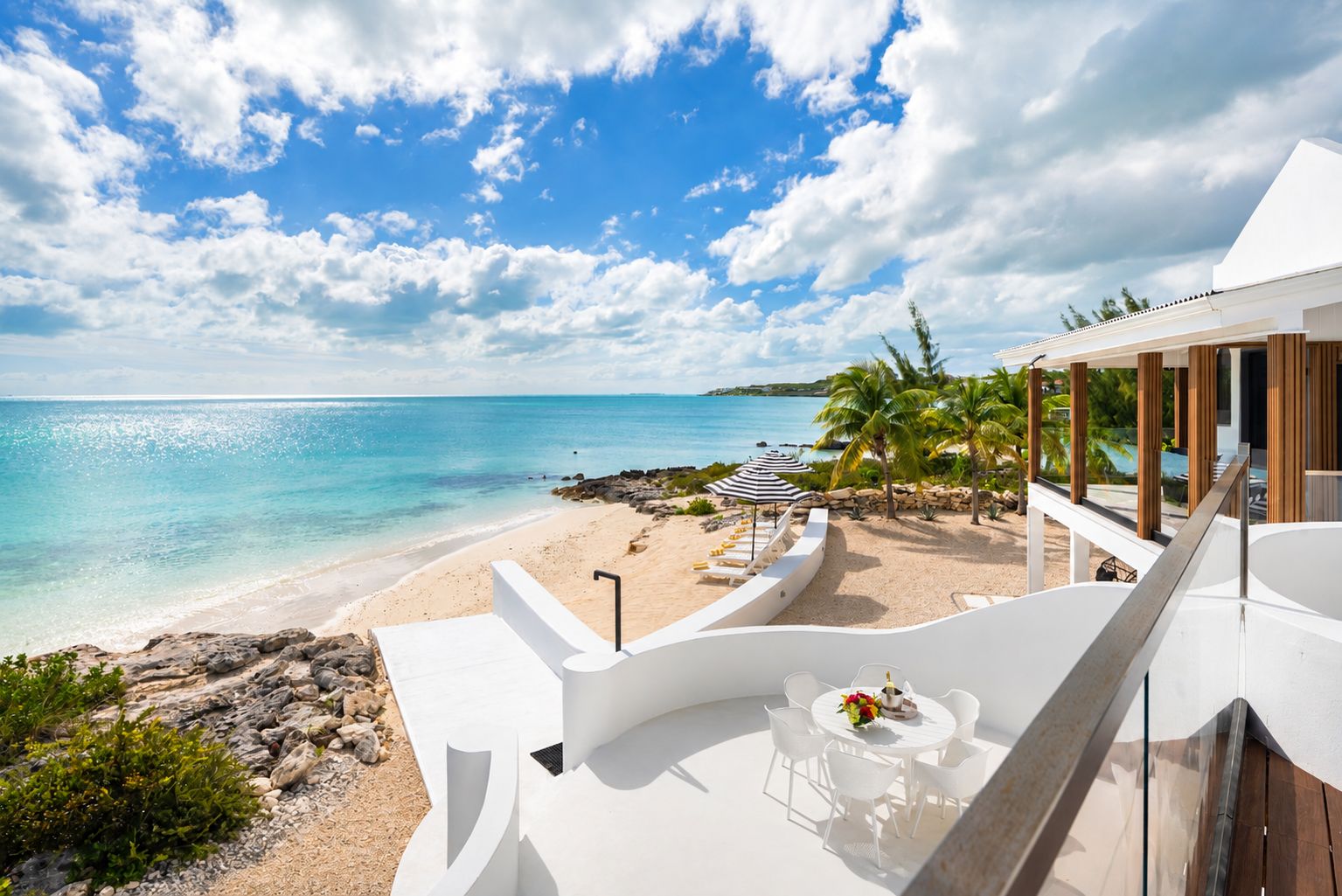 A beachfront property with a pool, lounge chairs, and a view of the ocean.