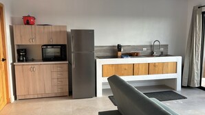 A compact kitchen with a microwave, refrigerator, and wooden cabinets. - CIMA DEL MAR #1 - Cozy downstairs poolside condo w/ ocean views in Samara center (Sámara)