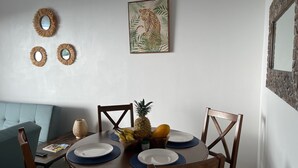 A dining area with a round wooden table, four chairs, and a pineapple centerpiece. - CIMA DEL MAR #1 - Cozy downstairs poolside condo w/ ocean views in Samara center (Sámara)