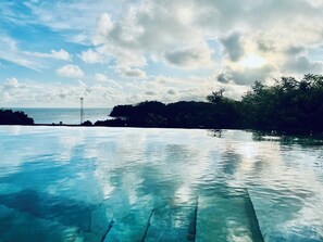 A clear view of an infinity pool with a view of the ocean and a distant tower.