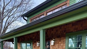 A house with a porch, wooden siding, and a swing chair.