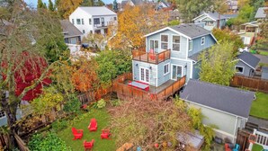 A two-story house with a fenced backyard, a deck, and a small garden area.