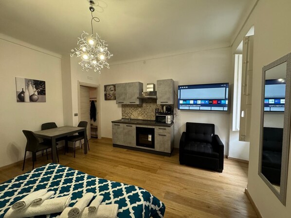 A modern apartment with a dining area, kitchenette, and a living space.