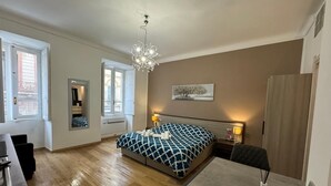 Un dormitorio moderno con una cama grande, mesitas de noche, un escritorio y una araña.