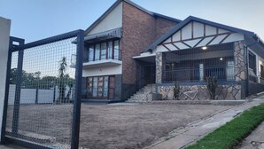 Een modern huis met twee verdiepingen, een stenen gevel, een balkon en een omheinde tuin.