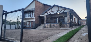 Uma casa moderna de dois andares com fachada de pedra, varanda e quintal cercado.