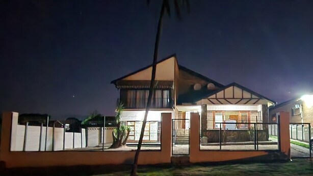 Een modern huis met een goed verlichte entree, een zichtbare trap en een omheinde tuin.