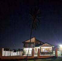 Uma casa moderna com uma entrada bem iluminada, uma escadaria visível e um quintal cercado.