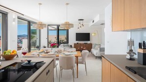 A modern kitchen with a dining area, large windows, and a view of the city.