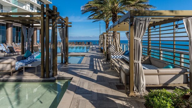 A poolside area with lounge chairs and a pool, overlooking the ocean.