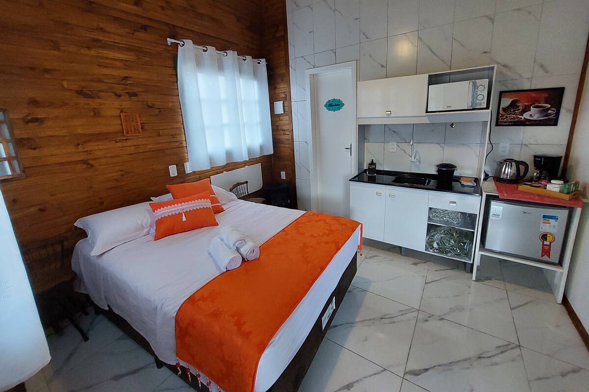 Une chambre comprenant un lit, une petite kitchenette et une salle de bain.