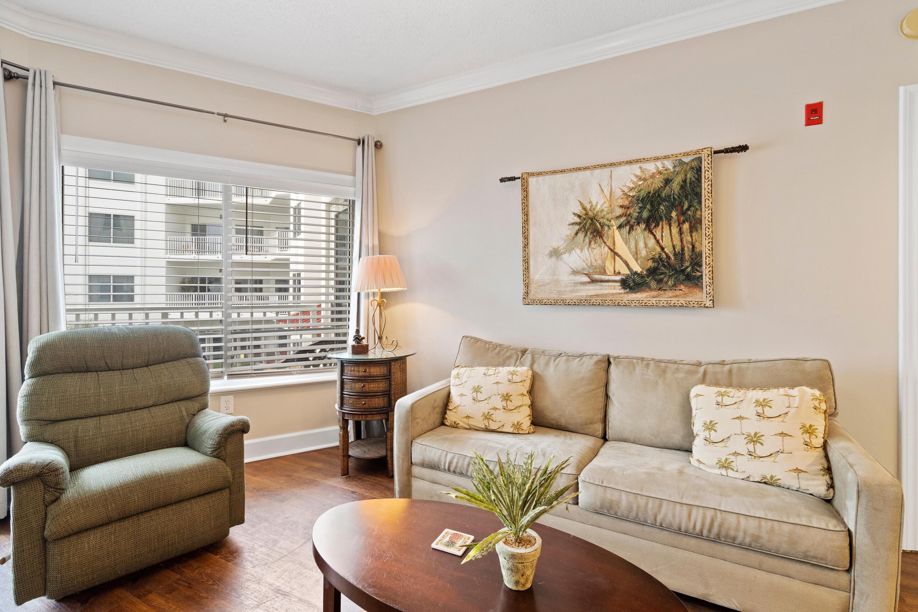 A living room with a sofa, armchair, and a table with a plant.