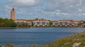 A waterfront hotel with a prominent tower, multiple buildings with red roofs, and a calm lake. - Holiday Home Near Beach With Sunny Terrace (Westkapelle)