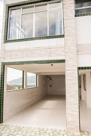 A two-story building with a covered outdoor area, a visible shower, and a view of the landscape.