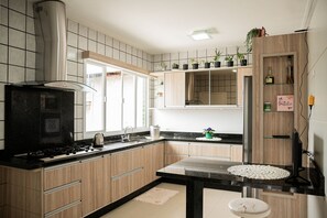 A modern kitchen with wooden cabinets, a black countertop, and a stainless steel range hood.