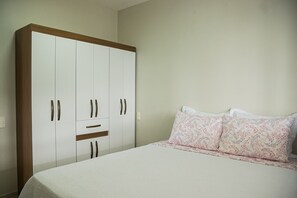 A bedroom with a bed, a large wardrobe, and a nightstand.