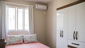 A bedroom with a bed, a wardrobe, and an air conditioning unit. - Morada Monte Verde - Florianópolis-SC (Florianópolis)