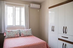 A bedroom with a bed, a wardrobe, and an air conditioning unit. - Morada Monte Verde - Florianópolis-SC (Florianópolis)