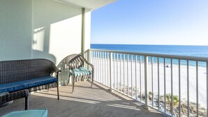 A balcony with a wicker sofa and chair, overlooking a beach. - Tradewinds 503 (Orange Beach)