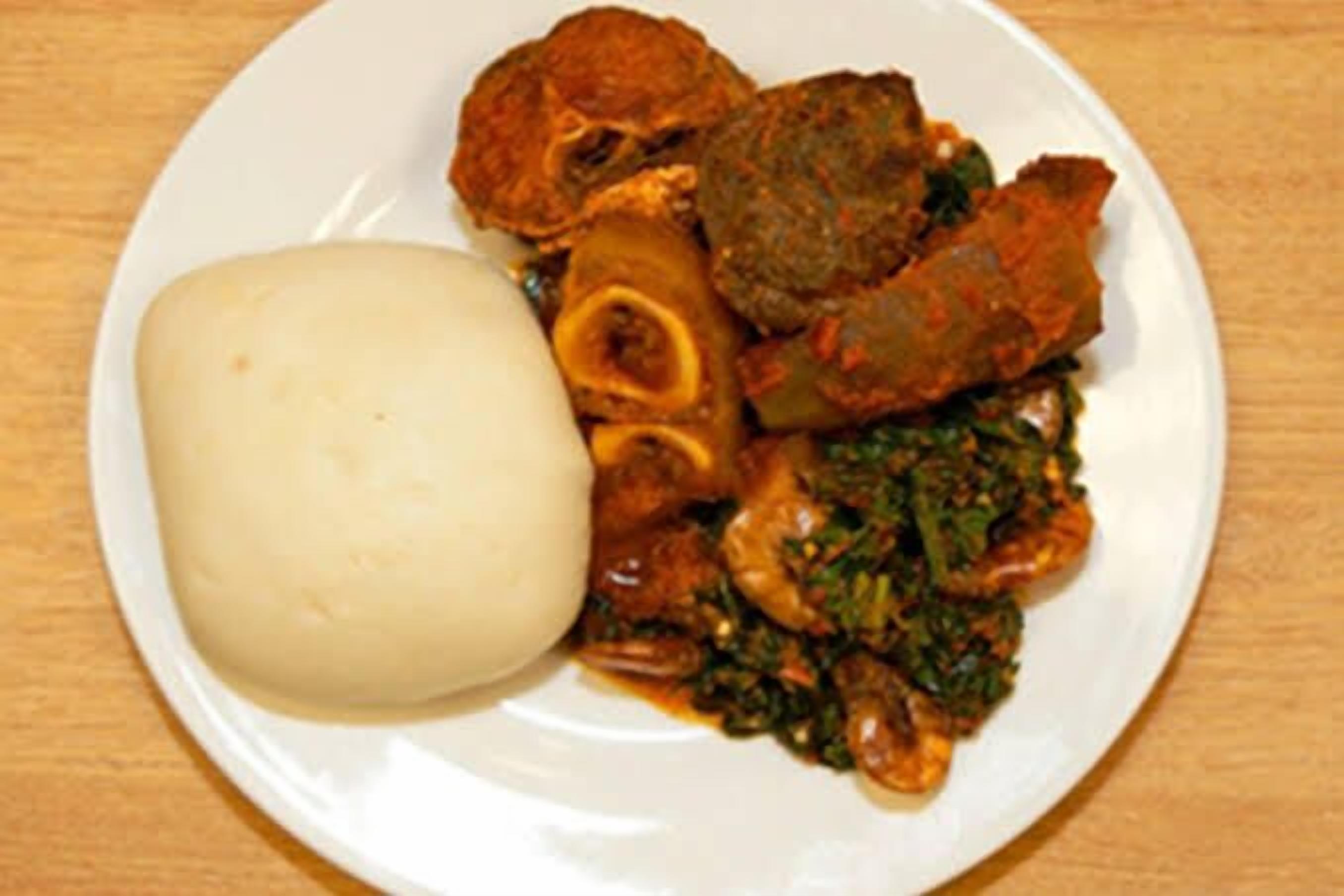 A plate with a variety of dishes including a large white item, possibly a bread or dumpling, and a mix of meats and greens.
