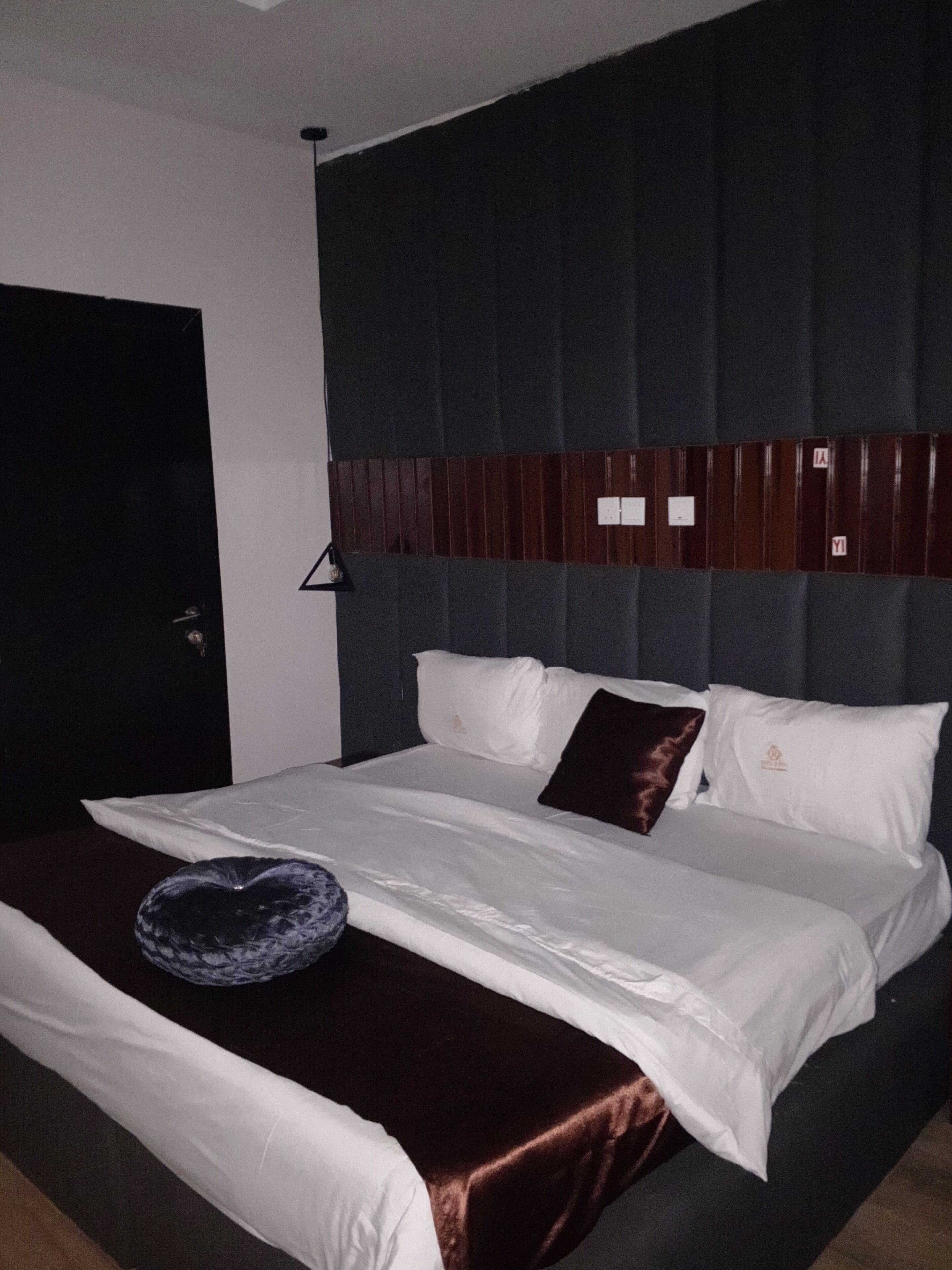 A hotel room with a large bed, dark headboard, and white bedding.