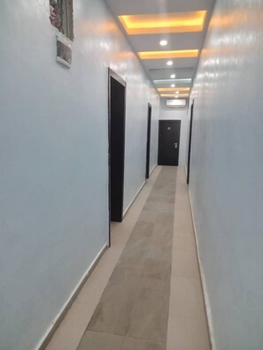 A hallway with light-colored walls and a tiled floor, leading to a door at the end.