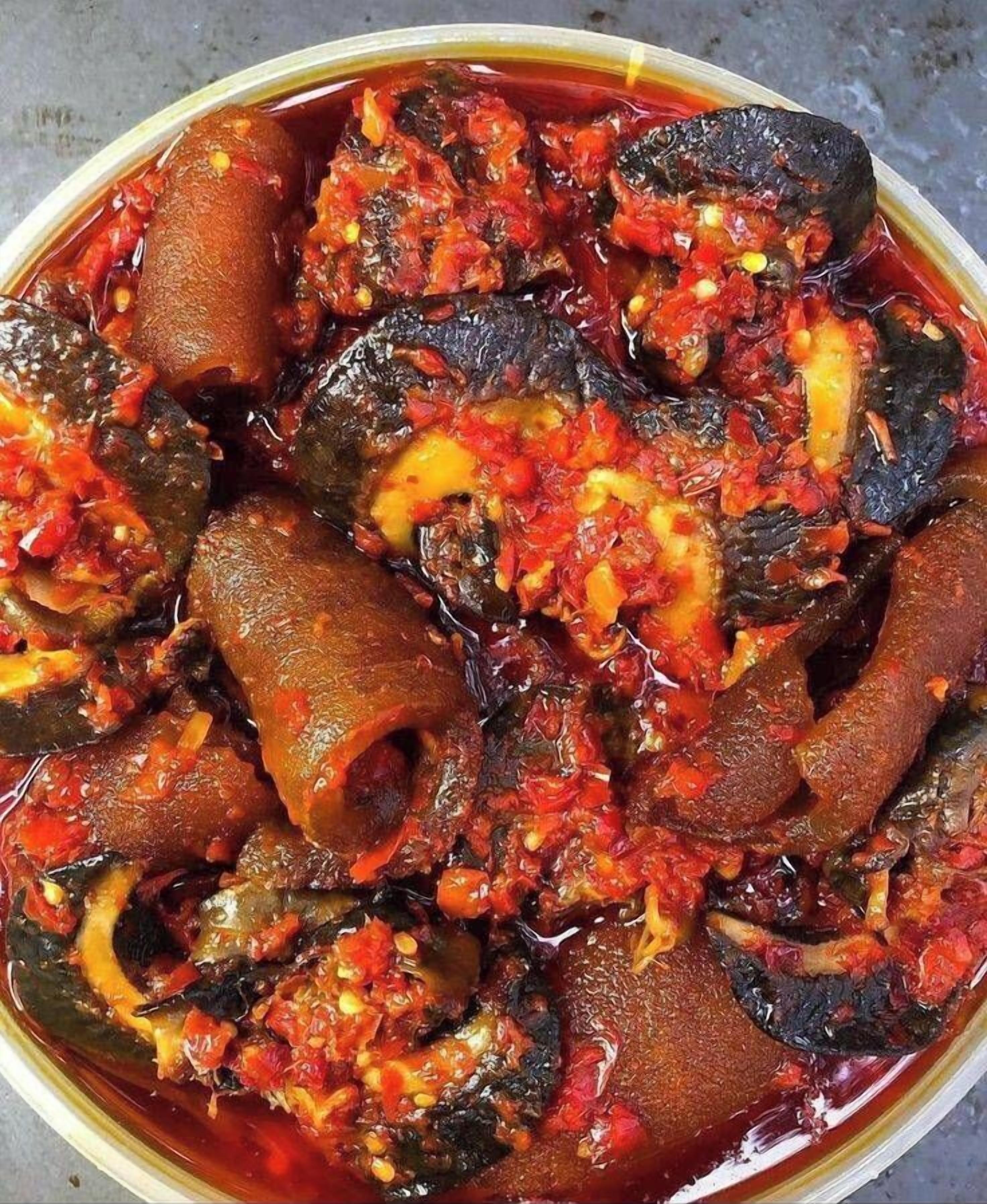 A bowl of cooked vegetables in a red sauce.