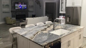 Una cocina moderna con una isla de mármol, electrodomésticos de acero inoxidable y un televisor de pantalla plana.