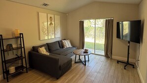 Una sala de estar con sofá, mesa de centro, televisor y estantería.