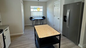 Una cocina compacta con una isla central, un refrigerador y una zona de comedor con sillas.