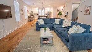 Una sala de estar moderna con un sofá modular, una mesa de centro y un televisor montado en la pared.